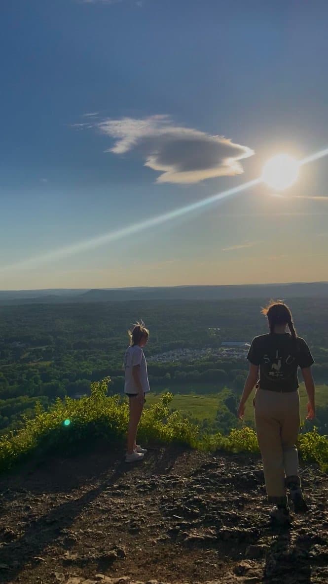 Two hikers at a hilltop overlook in the late-day sun