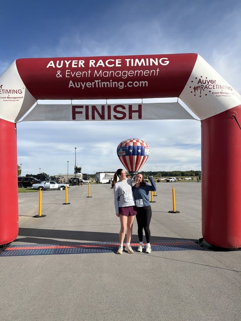 Remy and a friend at the finish line of a race, with a hot air balloon behind them