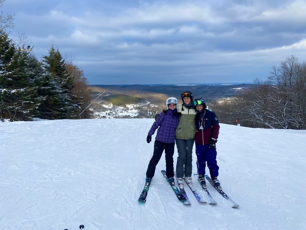 Remy and two friends on skis at the top of a snowy slope